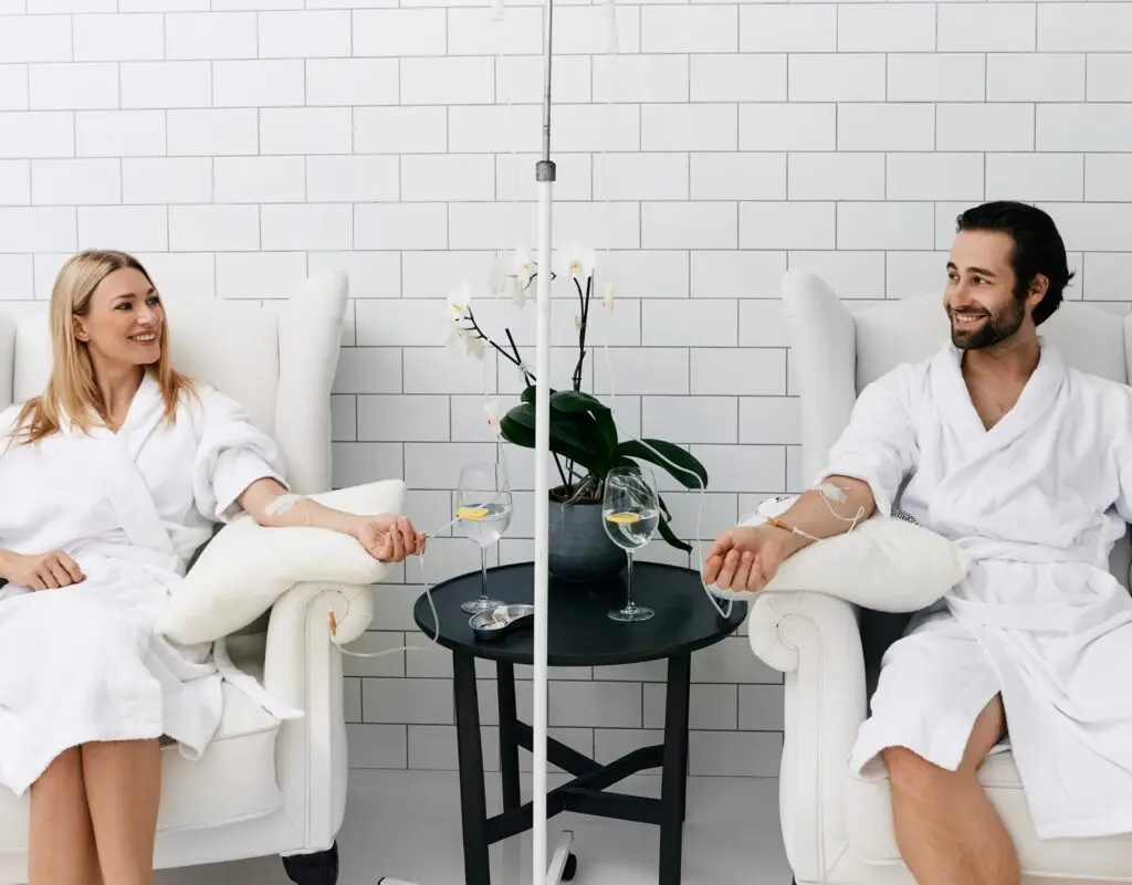 IV Therapy or Oral Supplements? 1 Couple receiving IV therapy in a clinic relaxed and happy